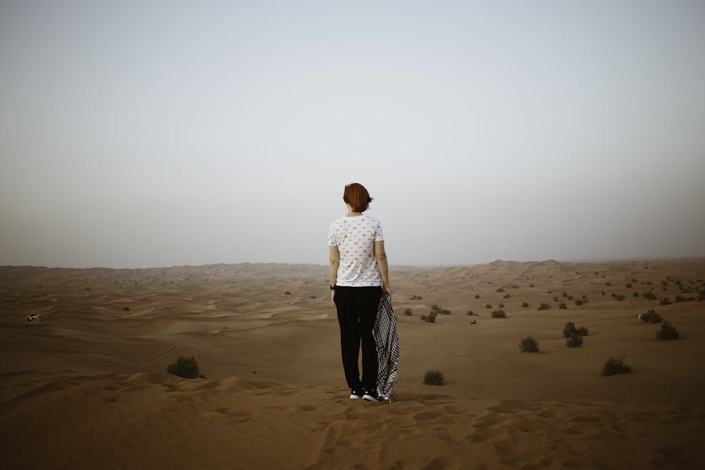 Unrecognizable woman in endless desert in overcast